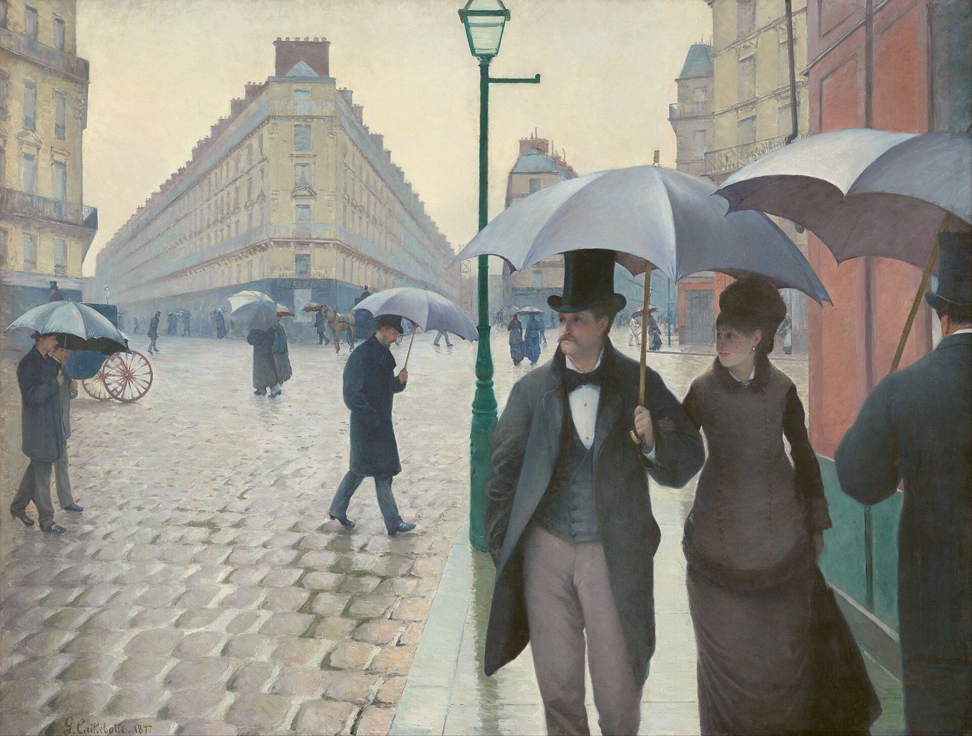 A couple under a black umbrella crossing wet cobbles at a wide Paris junction, pale stone buildings receding behind a green lamp post