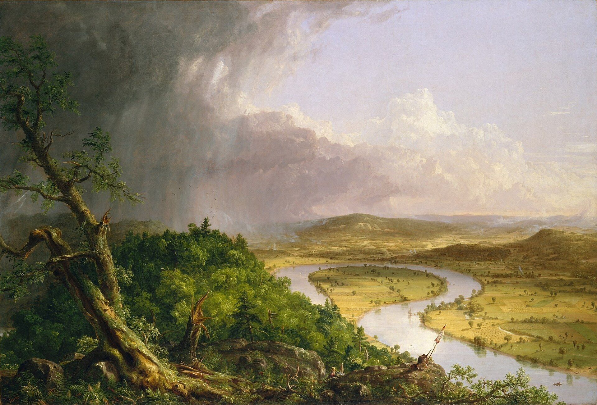 A broad river valley seen from a wooded height, sunlit farmland on the right and a storm still dragging rain across the dark left half