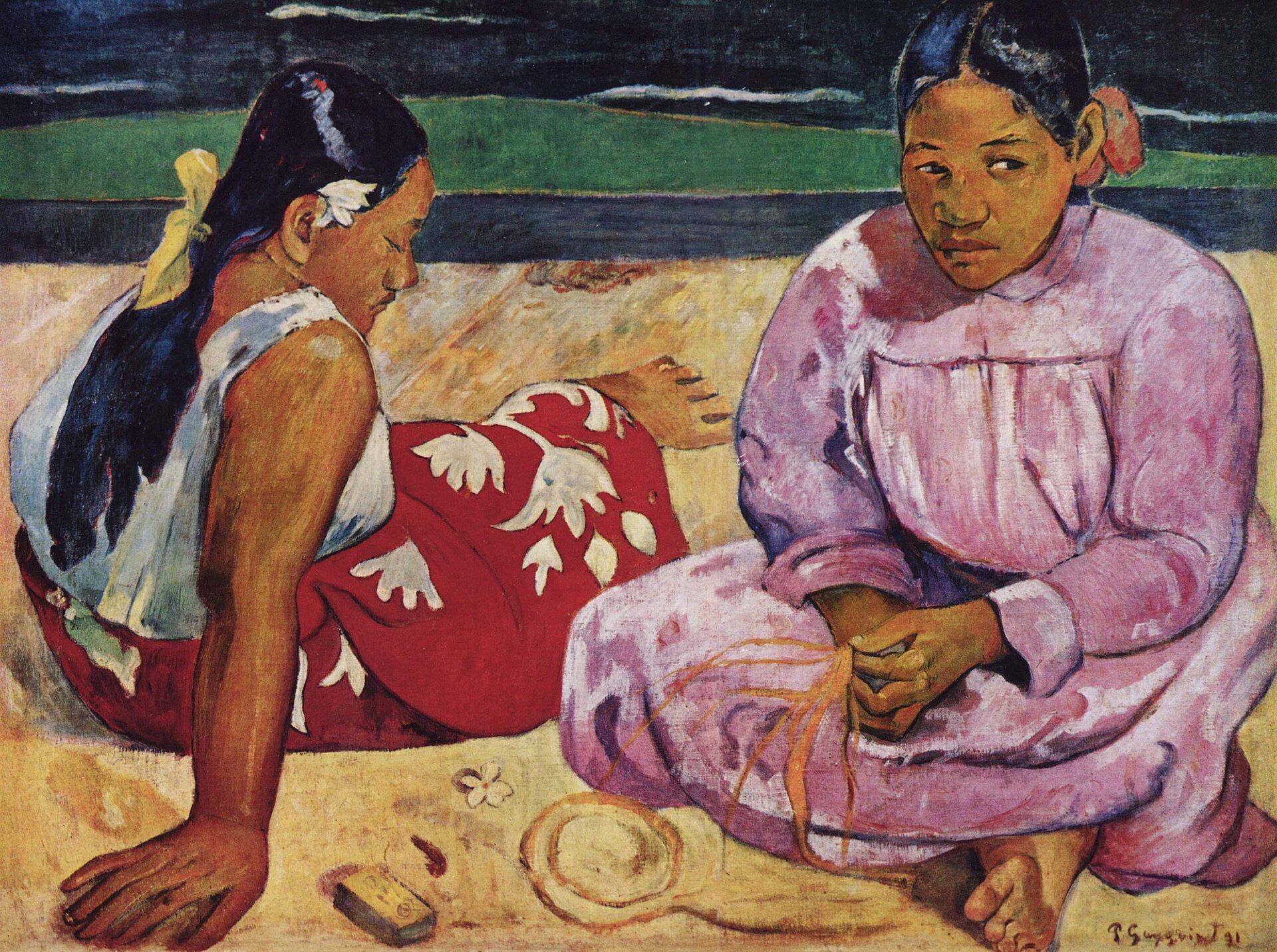 Two women seated on pink sand, one in a red and white printed wrap and one in a pale pink dress, a band of green and blue sea behind them