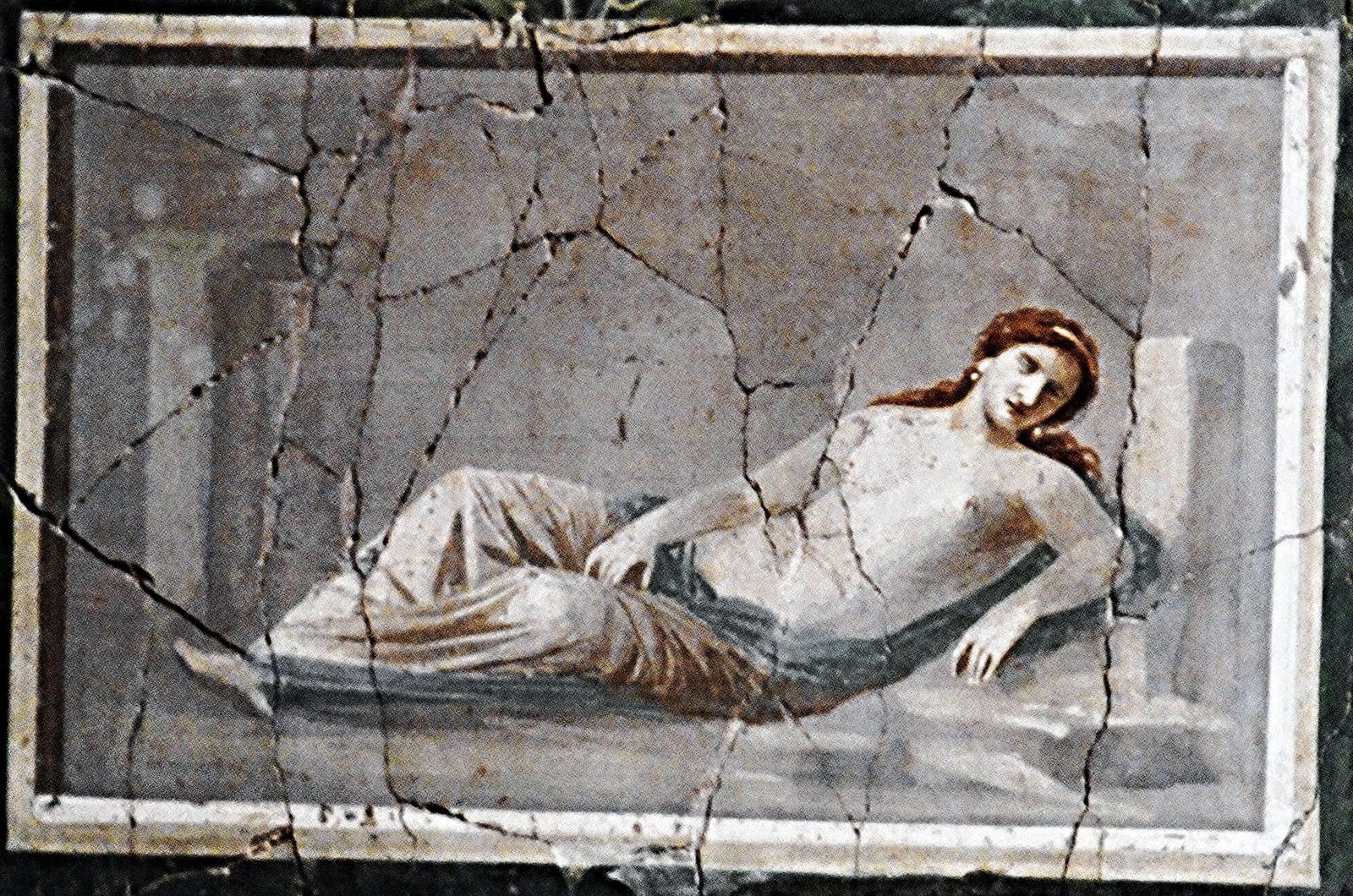 A reclining female figure in pale drapery, painted within a framed panel whose plaster is crossed by old cracks
