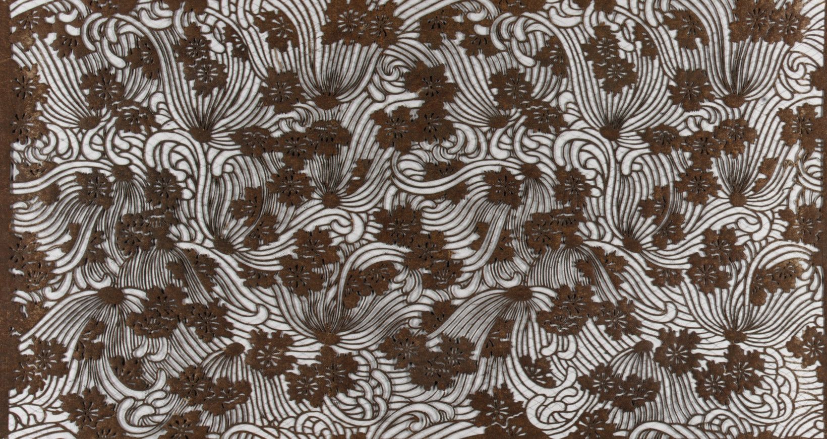 Small dark blossoms scattered over combed lines of wave, cut fine enough that the pattern reads as texture rather than as separate flowers