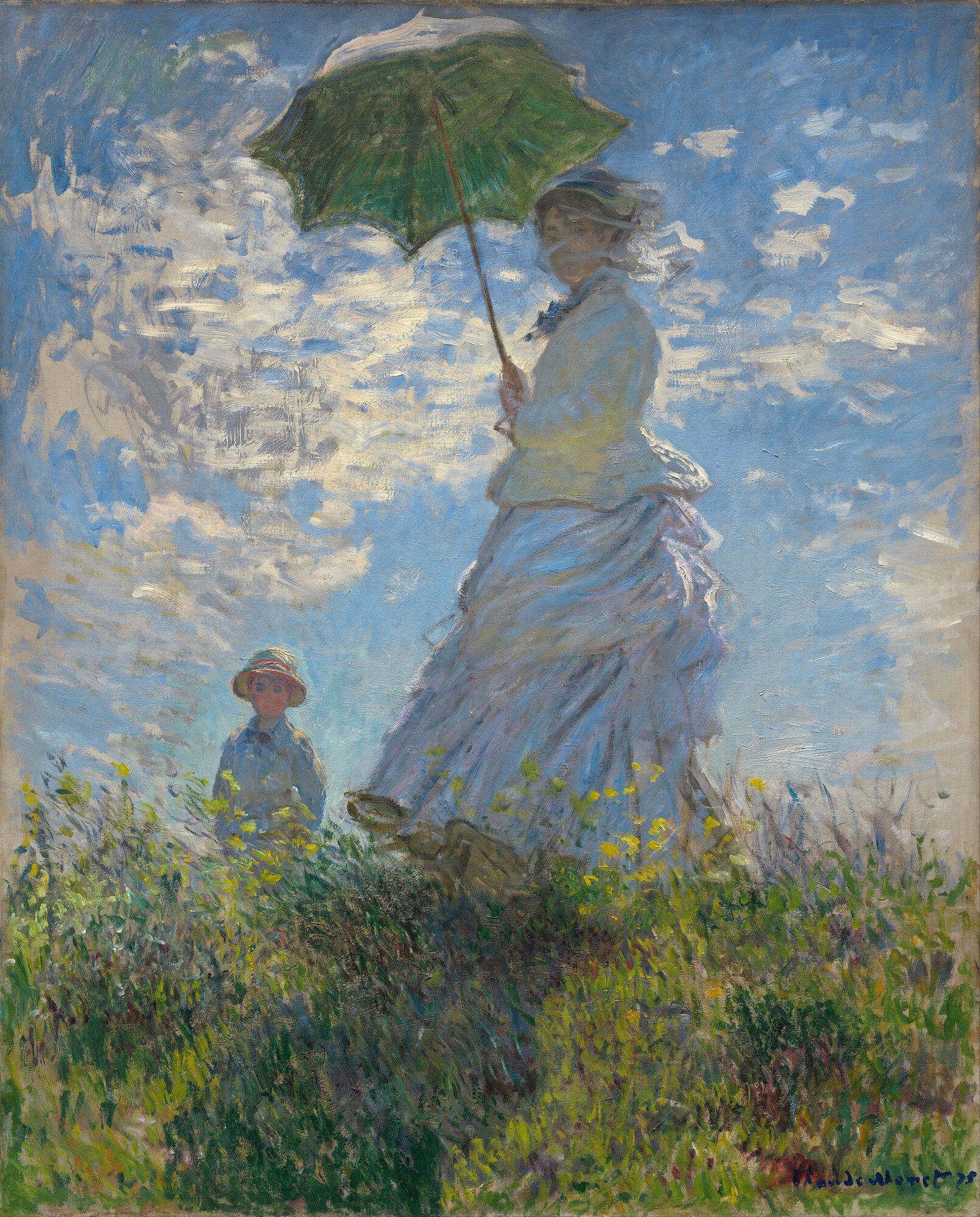 A woman on a grassy rise holding a green parasol against a windy blue sky, a child standing lower in the long grass
