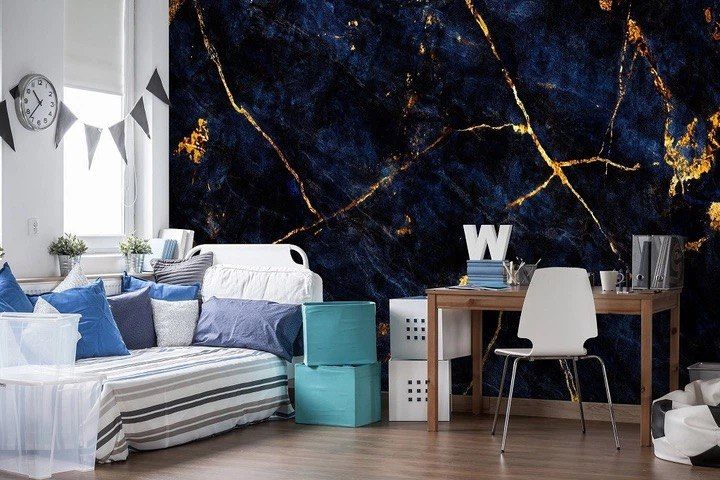 Wall panel of navy marble shot through with gold, behind a white bed and desk in a child's room