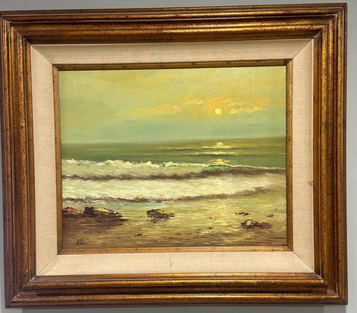 Sunset seascape with breaking surf running over dark rocks