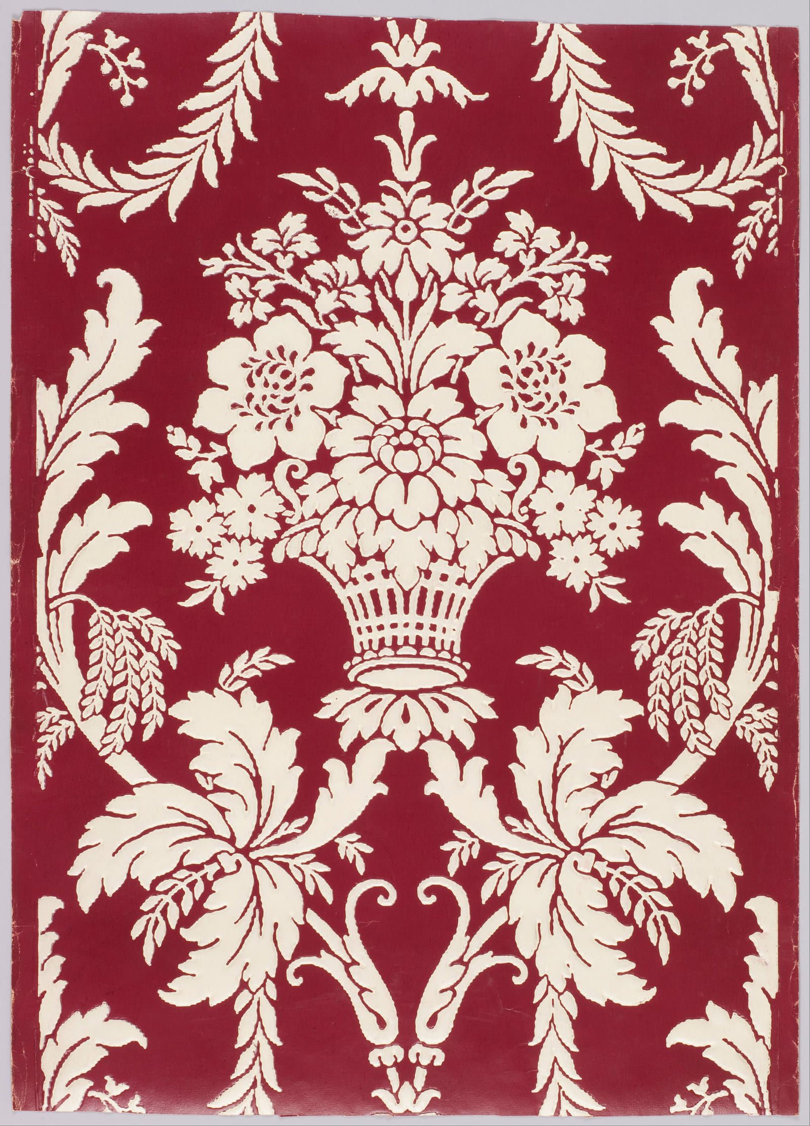 A cream basket of flowers with symmetrical scrolling foliage either side, printed on a deep crimson ground